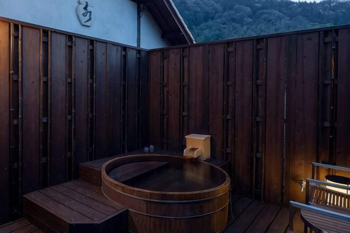 Eine Holzterrasse mit Whirlpool, Holzstufen und einer Sitzbank.
