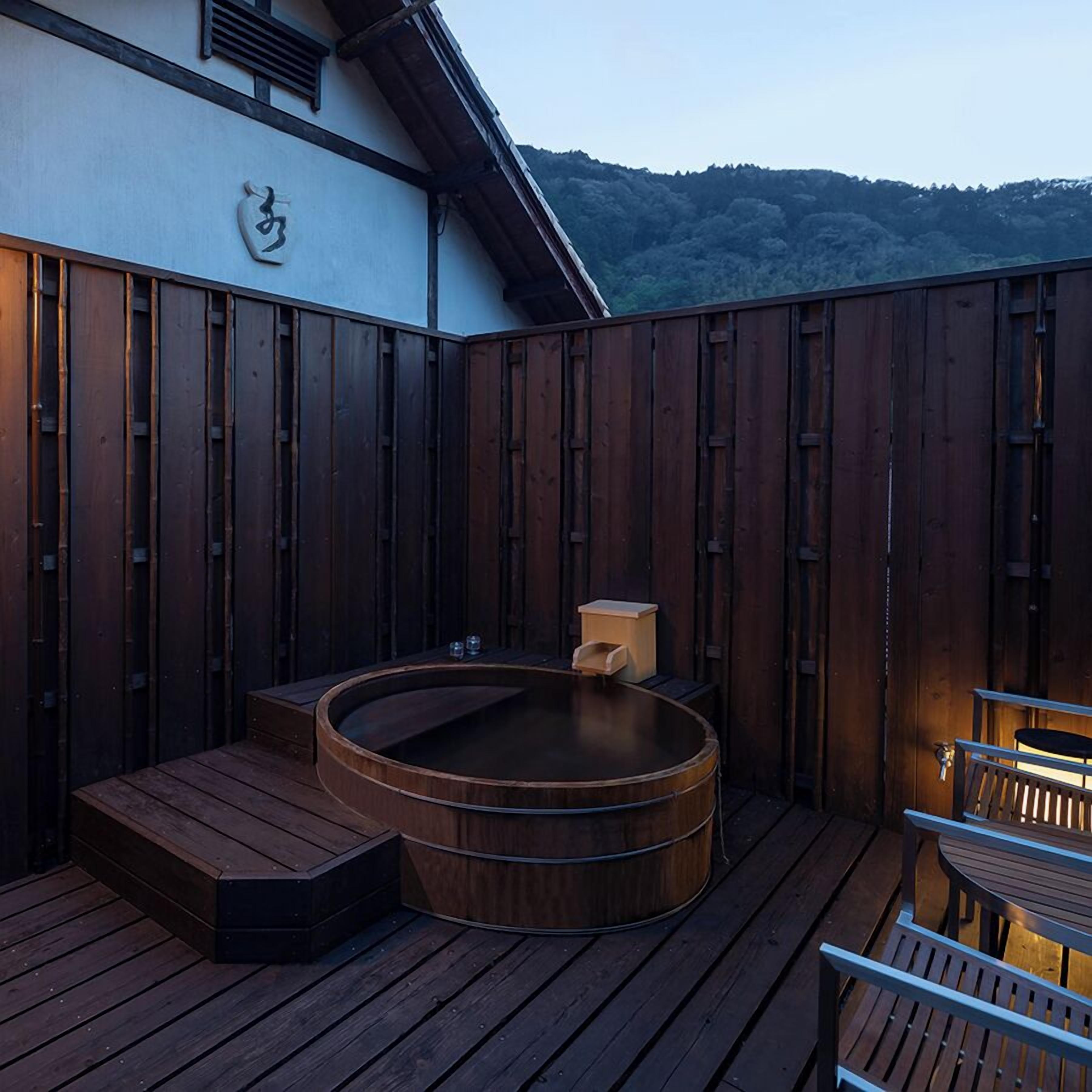 A wooden deck with a hot tub, a small table, and a bench.