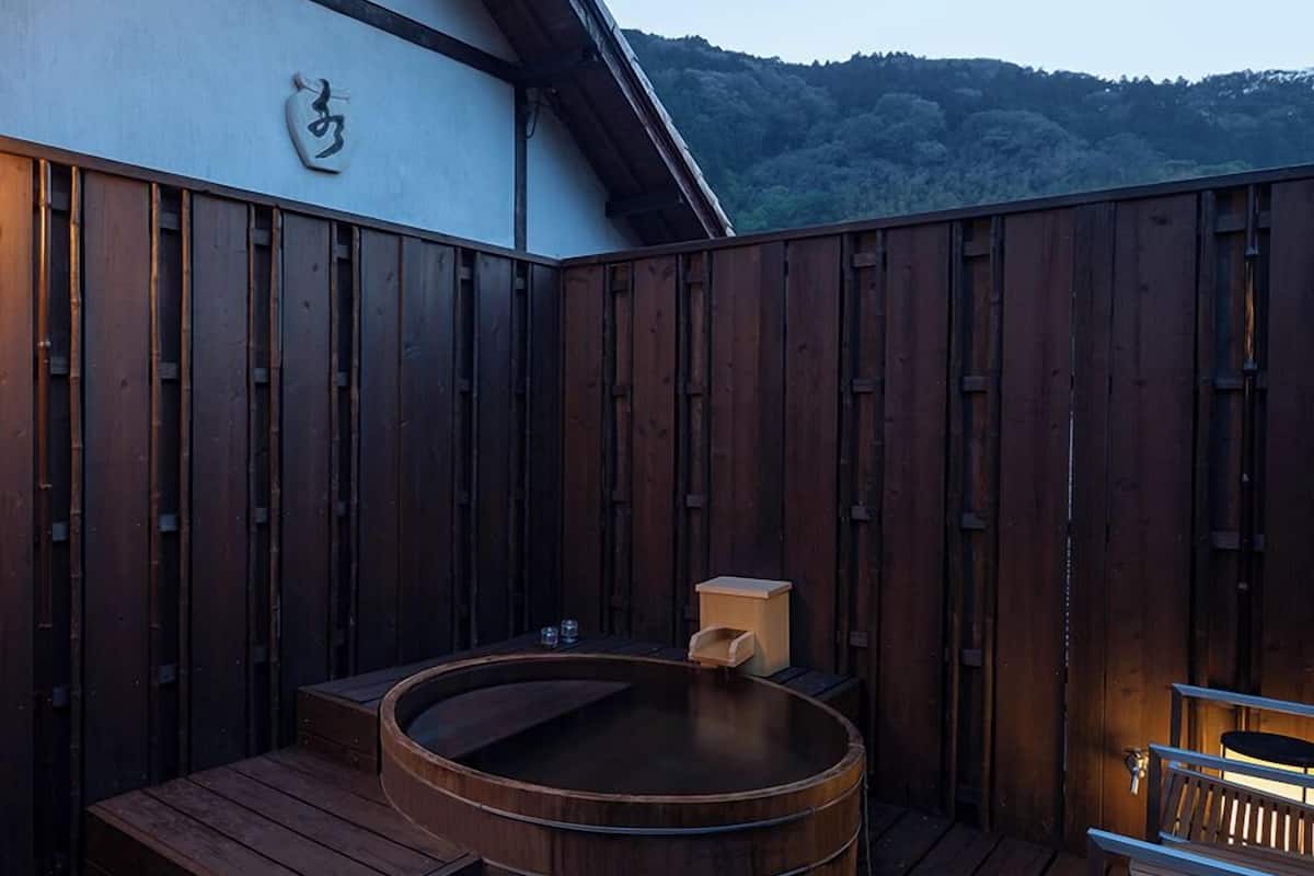Une terrasse en bois avec un jacuzzi, une petite table et un banc.