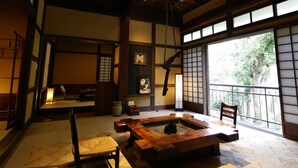 A traditional Japanese room with tatami flooring, a low wooden table, and a view of greenery outside. - Shirakabeso (Izu)