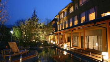 A hotel with a swimming pool, outdoor seating, and a view of the surrounding trees.