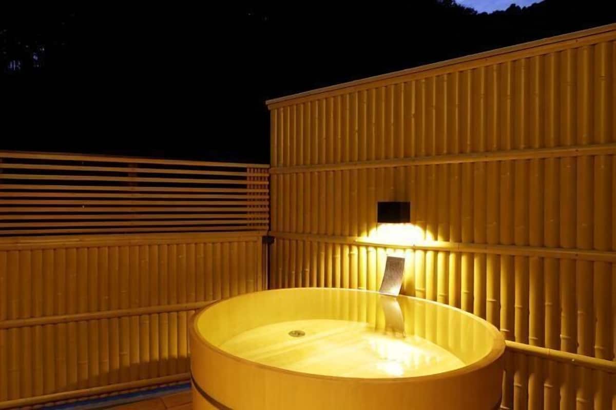 Ein Whirlpool mit einer darüberliegenden Lichtquelle, umgeben von einem Bambuszaun.