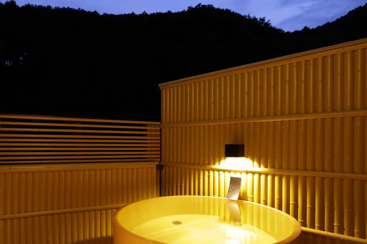 Ein großes, fassförmiges Whirlpool aus Holz mit einer Beleuchtung im Inneren, umgeben von Holzverkleidungen.