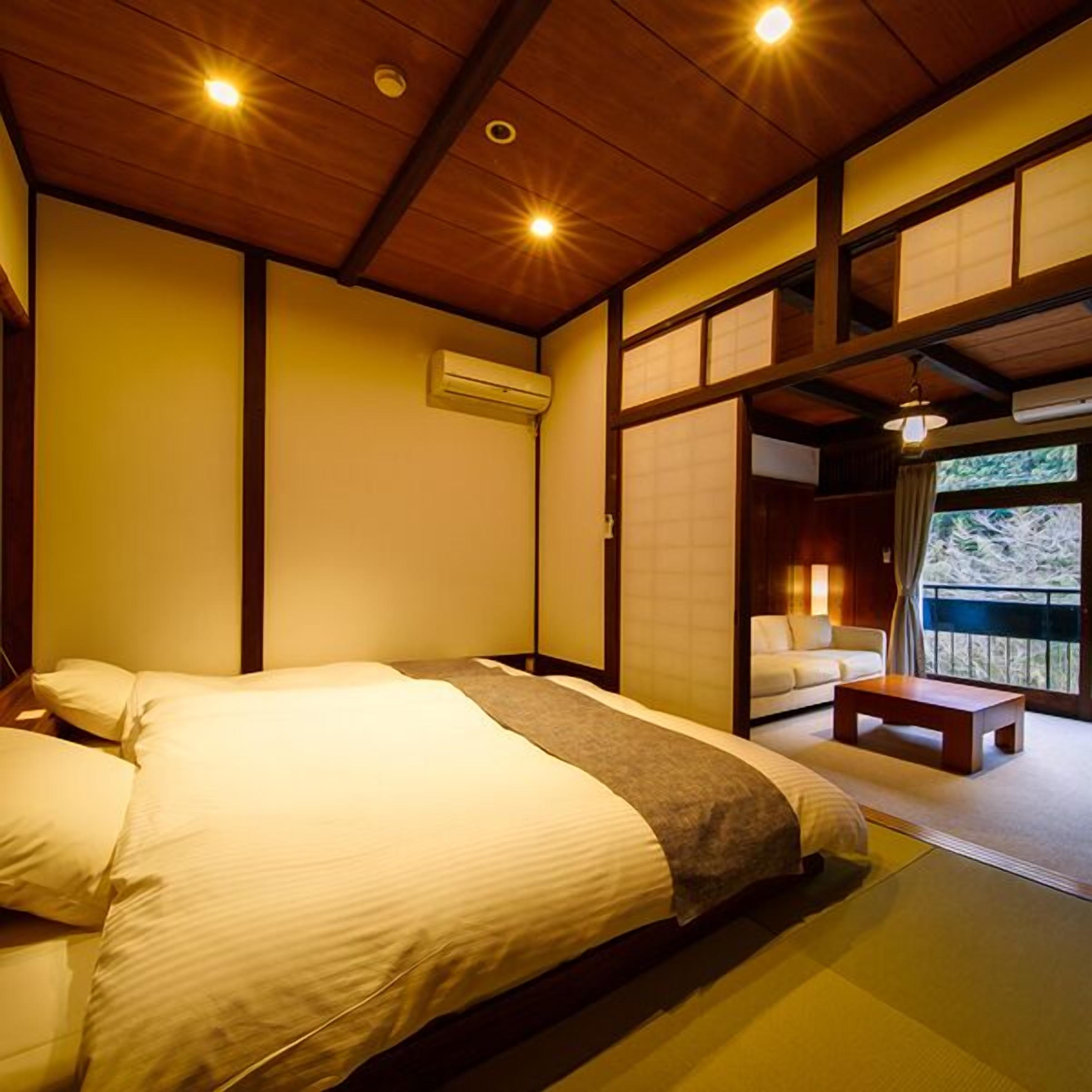 Een traditionele Japanse slaapkamer met een bed, een klein tafeltje en een schuifdeur naar een balkon.