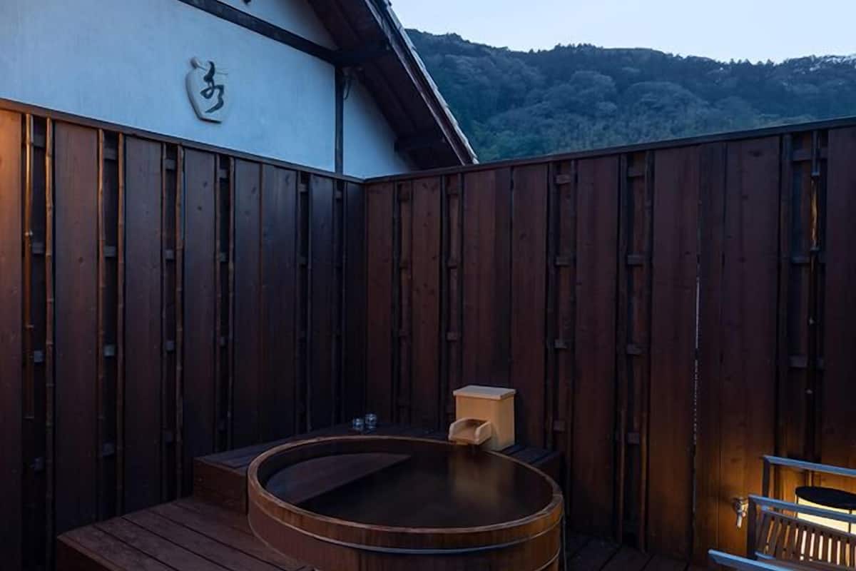 Eine Holzterrasse mit Whirlpool, einer Holzbank und einem Tisch mit Stühlen.