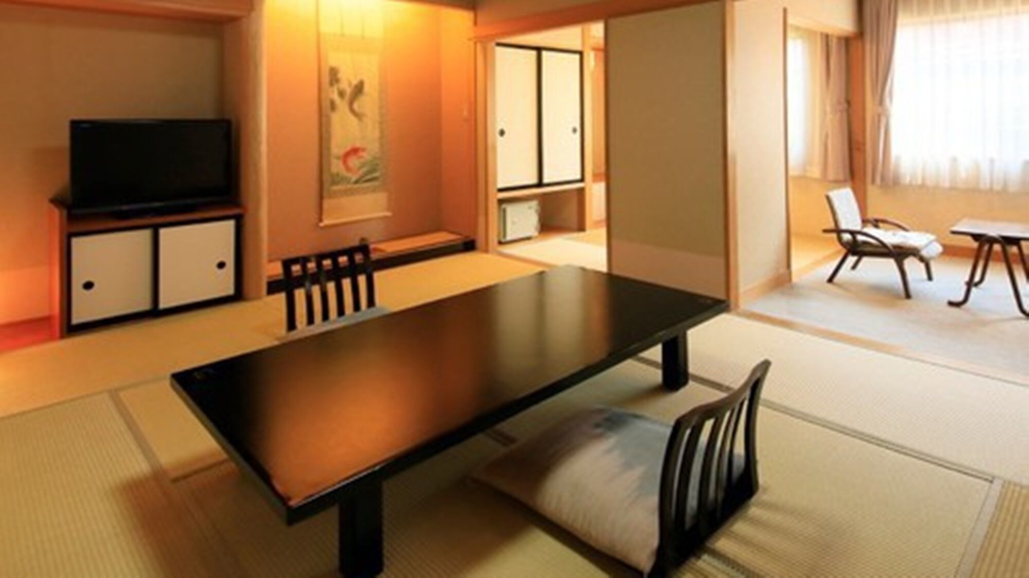 A traditional Japanese-style room with tatami flooring, a low table, and a television.