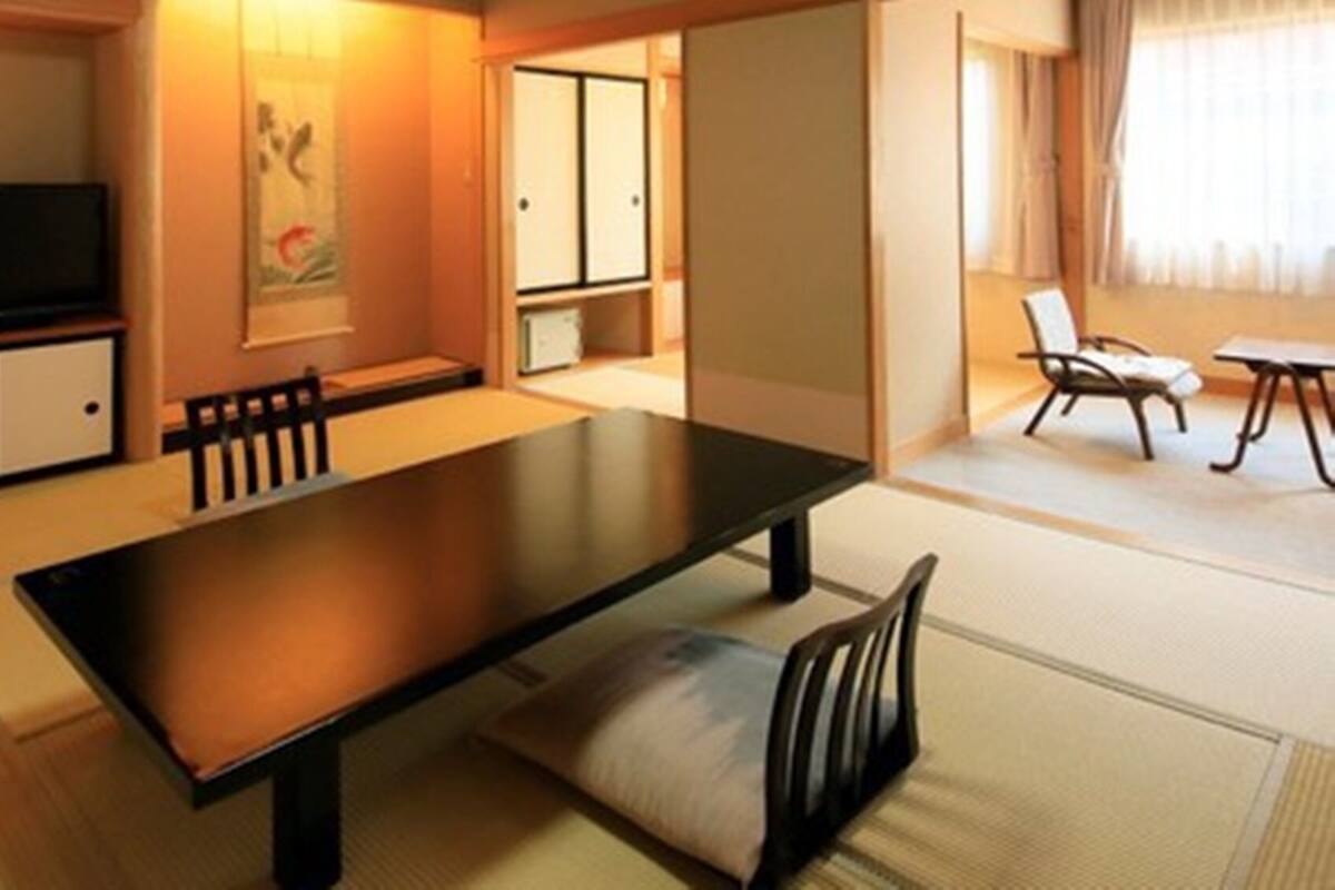 A traditional Japanese-style room with tatami flooring, a low table, and a television.