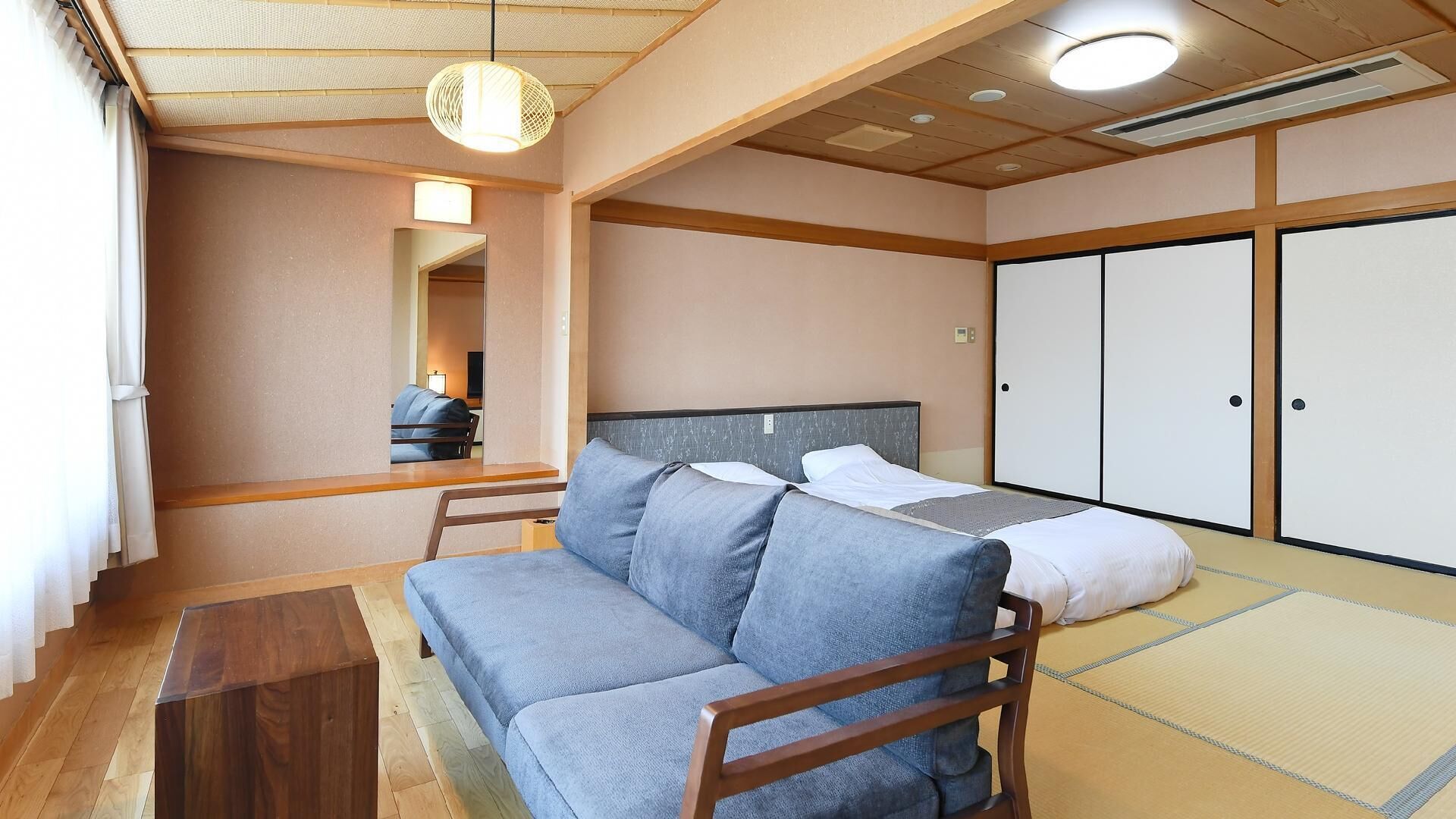 A room with a sofa, a bed, a wooden table, and a wardrobe.