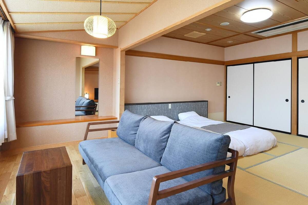 A room with a sofa, a bed, a wooden table, and a wardrobe.