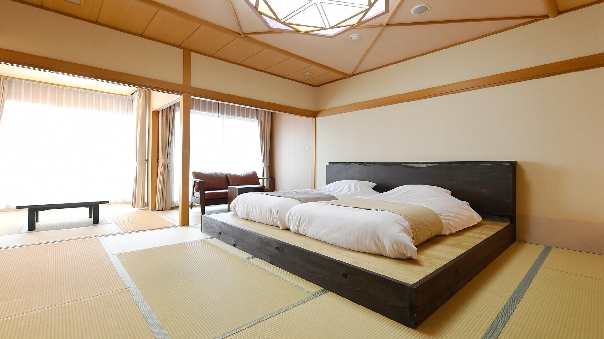 A traditional Japanese-style room with tatami flooring, a low platform bed, a bench, and a sliding door.