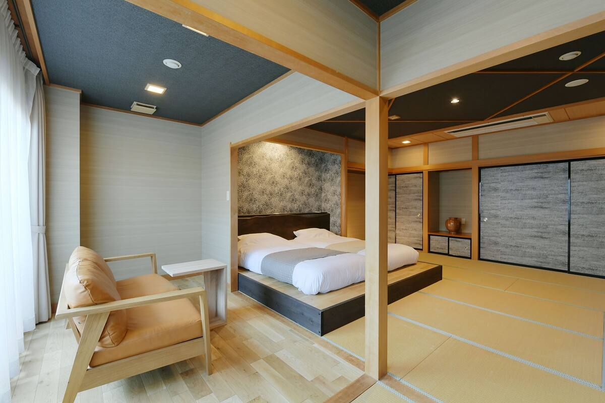 A modern hotel room with a bed, a seating area, and a tatami mat floor.