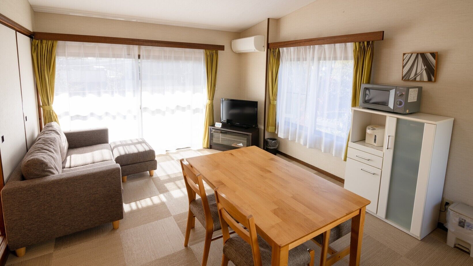 Ein Wohnzimmer mit einer Couch, einem Holztisch, einem Fernseher und einer Mikrowelle.