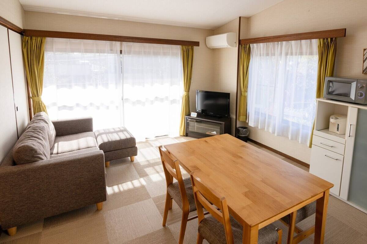 Ein Wohnzimmer mit einer Couch, einem Holztisch, einem Fernseher und einer Mikrowelle.