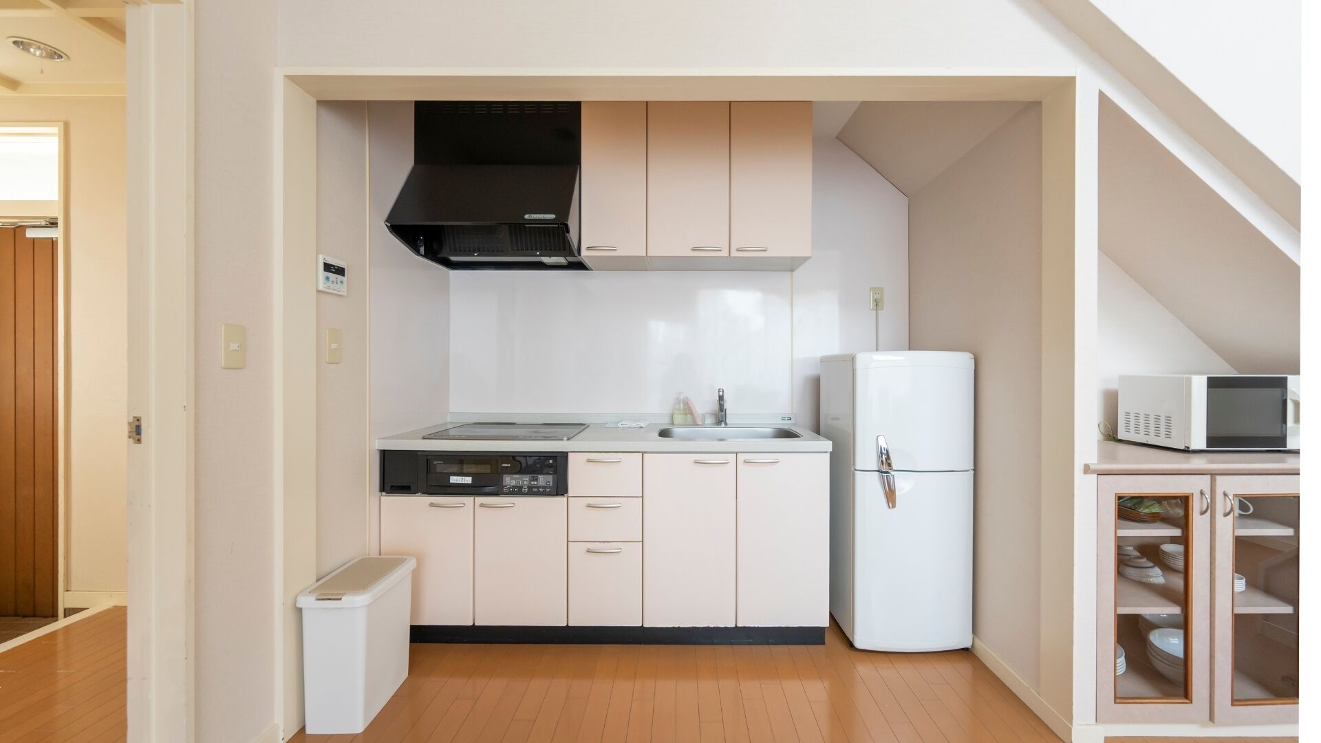Cozinha compacta com micro-ondas, geladeira e lava-louças.