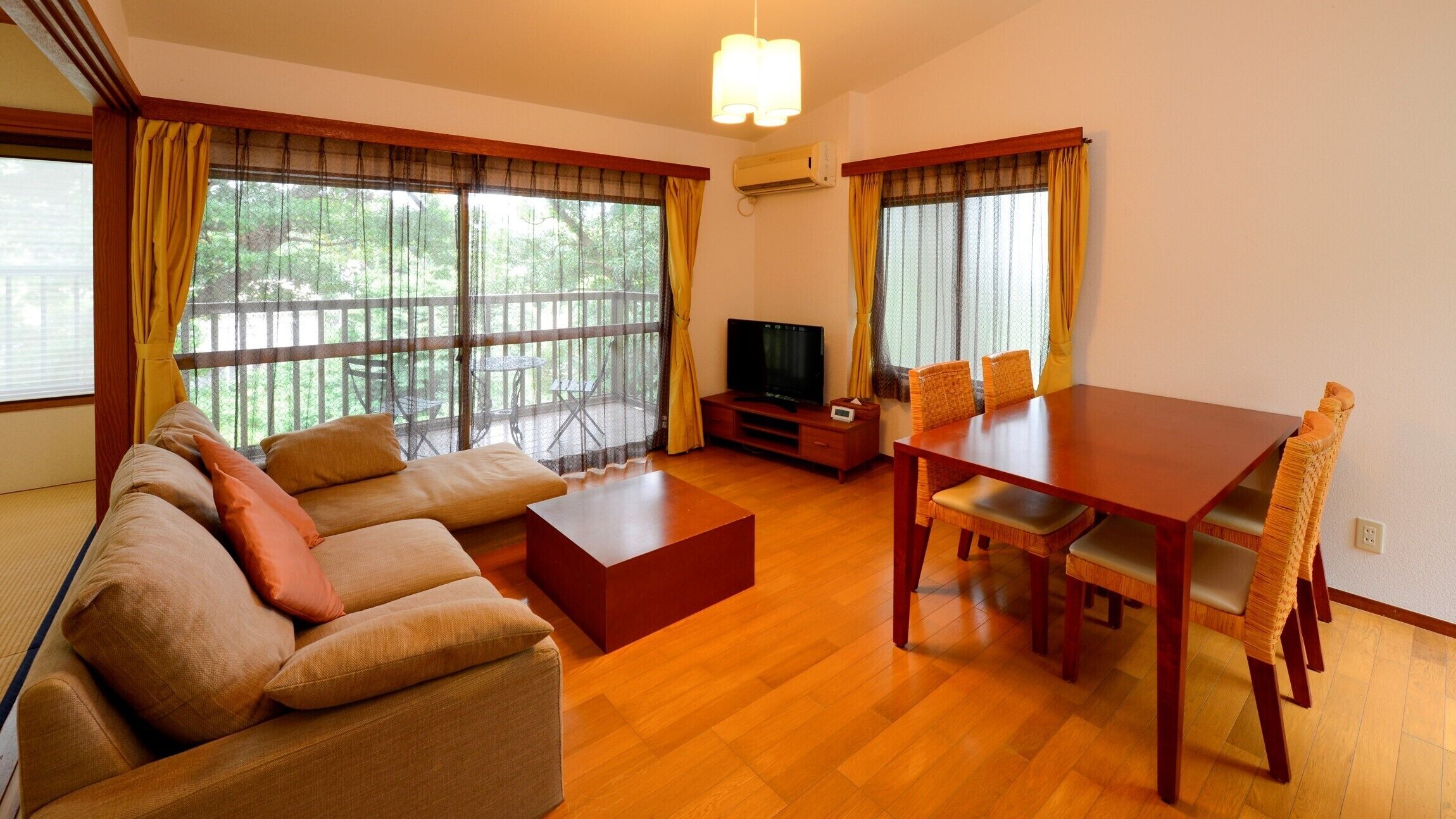 Uma sala de estar com sofá, televisão, mesa de jantar e cadeiras.