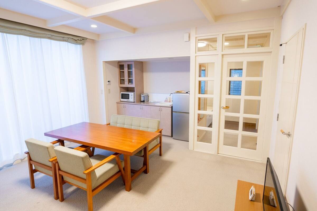Ein kompakter Wohnbereich mit Essplatz, Küchenzeile und einer Glastür zum Balkon.