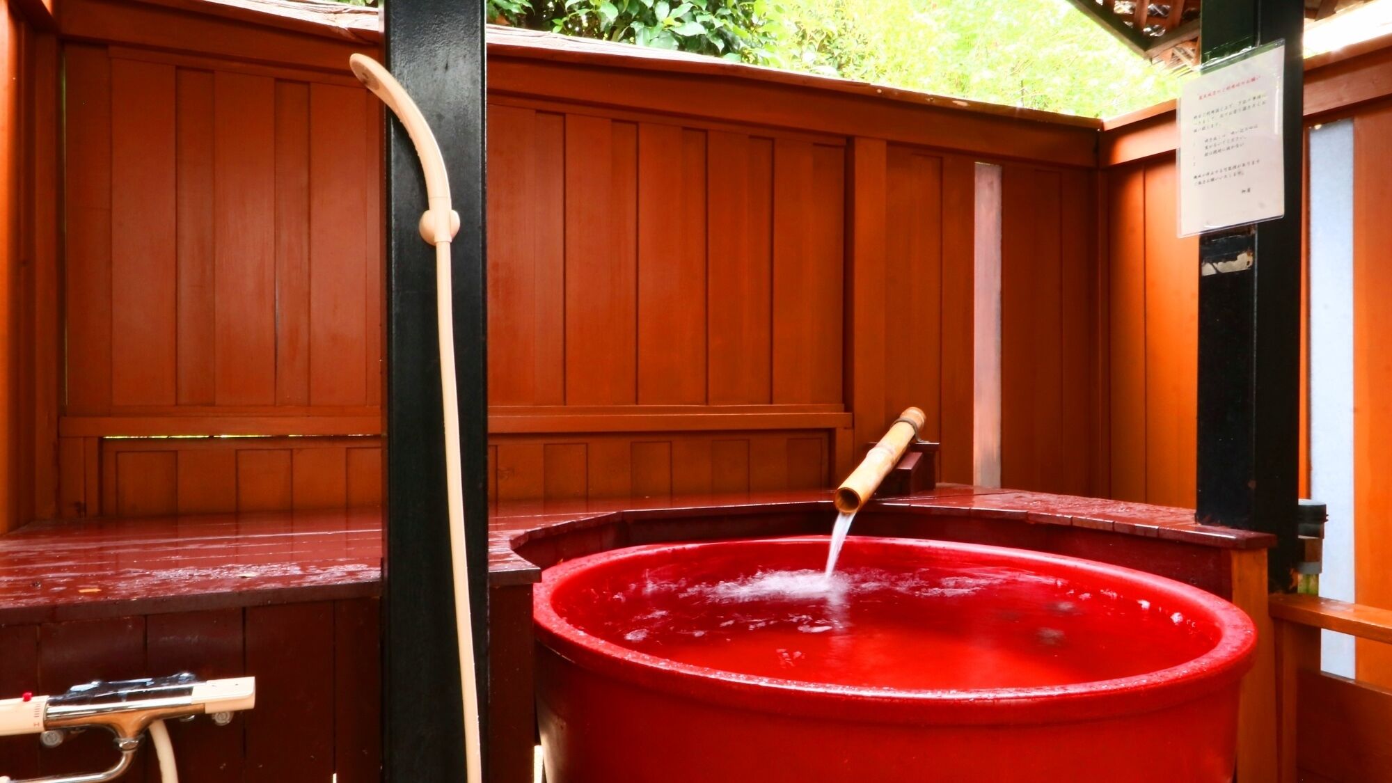 A red hot tub with a wooden bench and a black post.