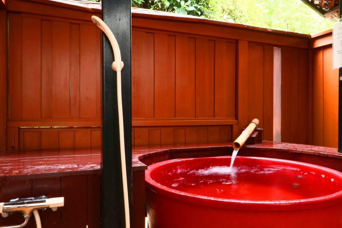 A red hot tub with a wooden bench and a black post.