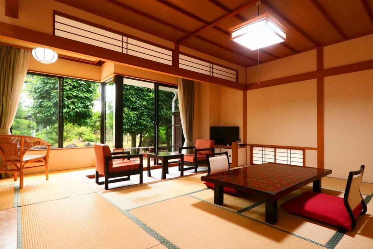 Una habitación japonesa tradicional con suelo de tatami, una mesa baja y puertas correderas.