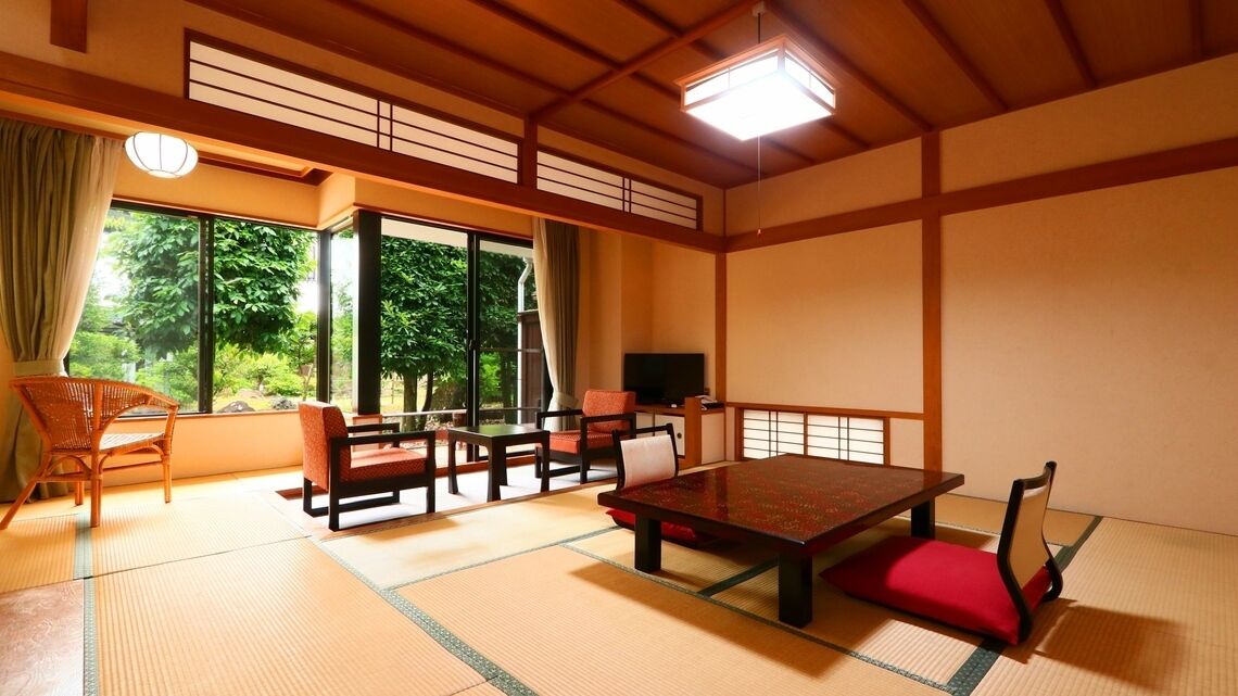 Una habitación japonesa tradicional con suelo de tatami, una mesa baja y puertas correderas.
