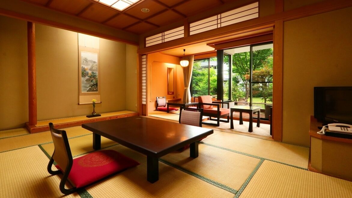 Una habitación japonesa tradicional con suelo de tatami, una mesa baja y una puerta corredera que da a un espacio al aire libre.