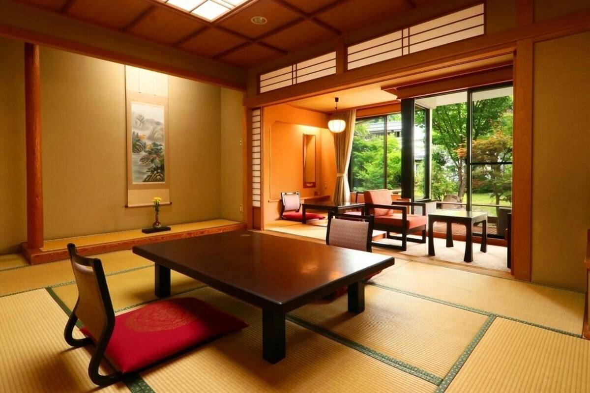 A traditional Japanese room with tatami flooring, a low table, and a sliding door leading to an outdoor area.