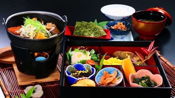 Uma tradicional caixa-refeição japonesa com diversos alimentos, incluindo peixe, legumes e arroz.