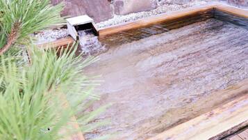 Una fuente de agua con una estructura de madera y un pequeño desagüe.