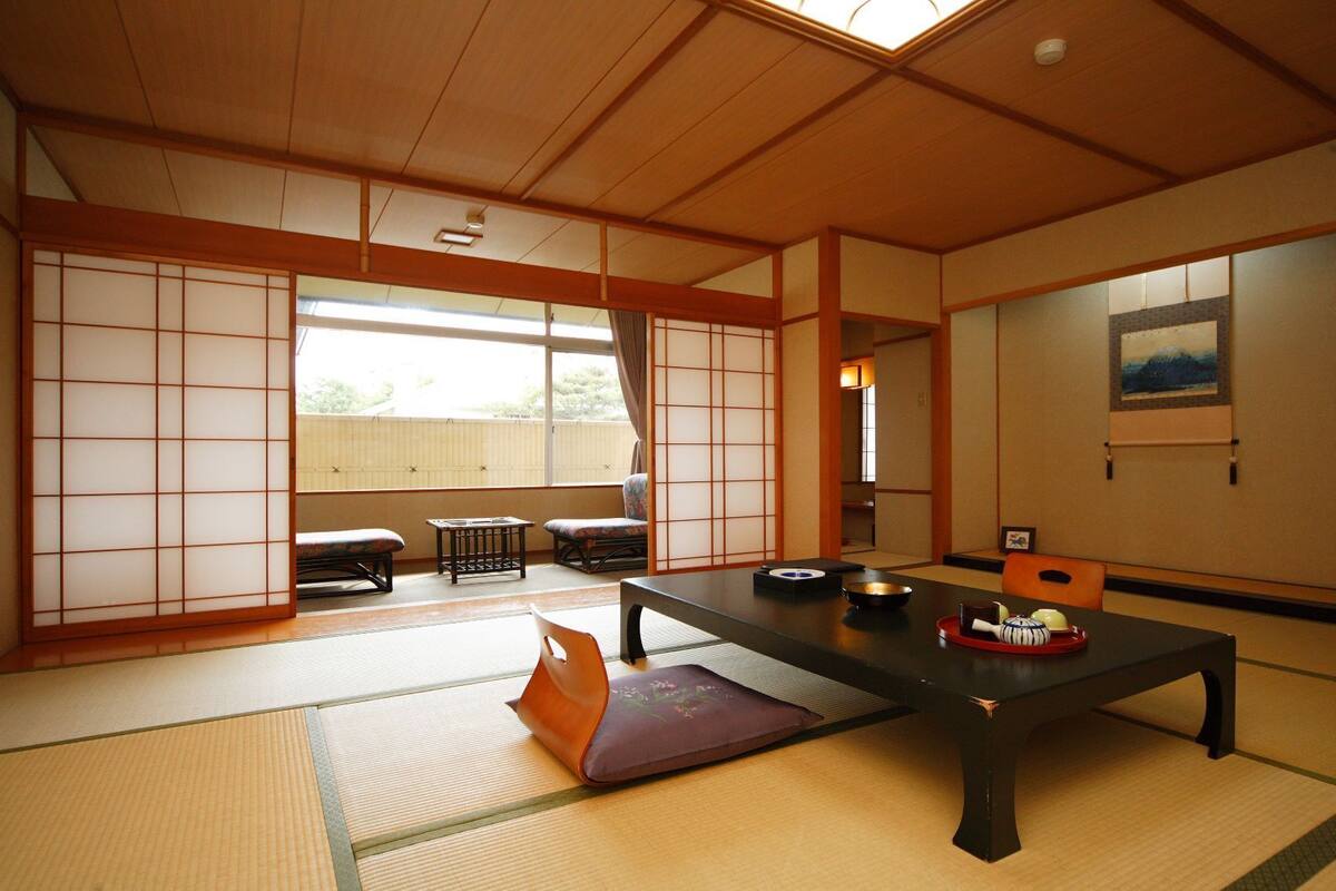 Une pièce de style japonais traditionnel, avec un sol recouvert de tatamis, une table basse et des portes coulissantes.