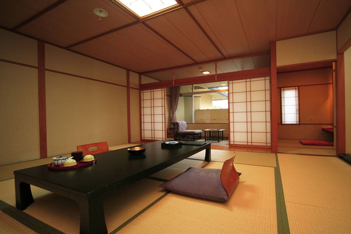 Une pièce de style japonais traditionnel, avec un sol recouvert de tatamis, une table basse et des portes coulissantes.