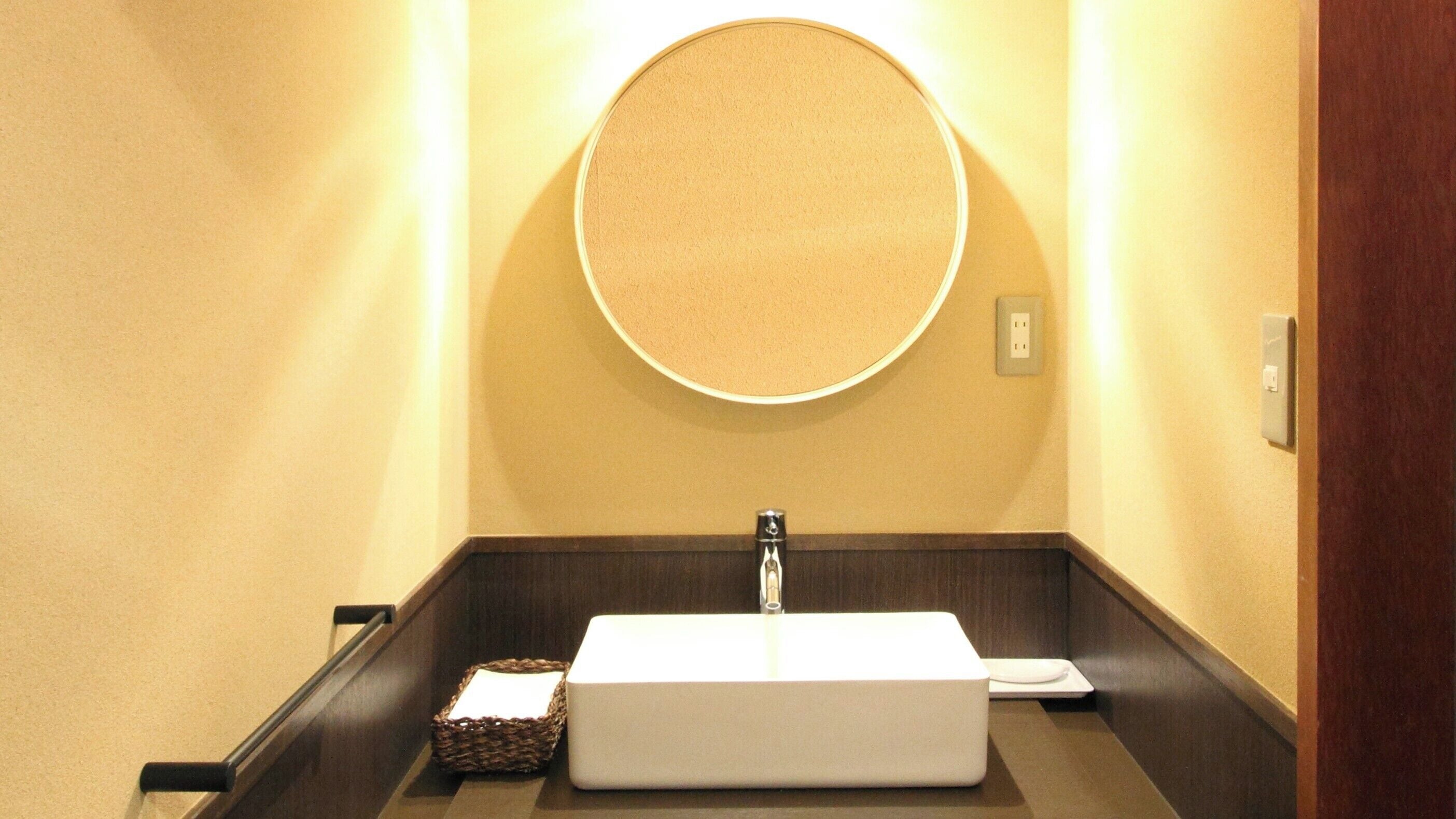 Un bagno con un lavabo rettangolare, uno specchio rotondo e un lampadario a parete.