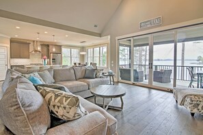 A spacious living room with a large sectional sofa, a round coffee table, and a balcony with a view of a lake. - Lake Keowee Home with Balcony & Boat Dock! (Seneca)