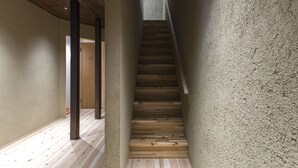 Un escalier étroit avec des marches en bois et un mur à texture sur un des côtés.