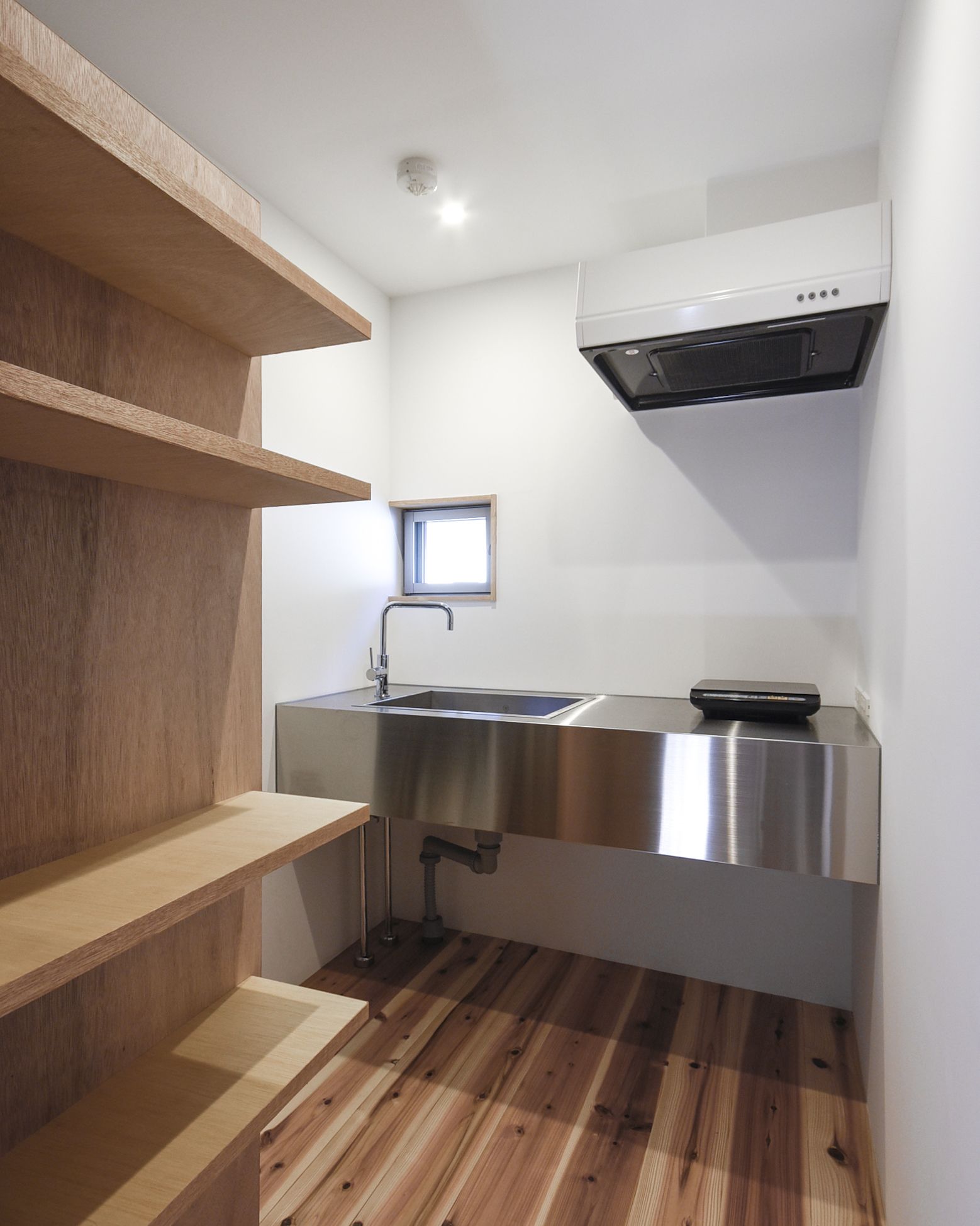 A compact kitchen with a stainless steel sink, a window, and a built-in oven.