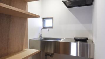 A compact kitchen with a stainless steel sink, a window, and a built-in oven.