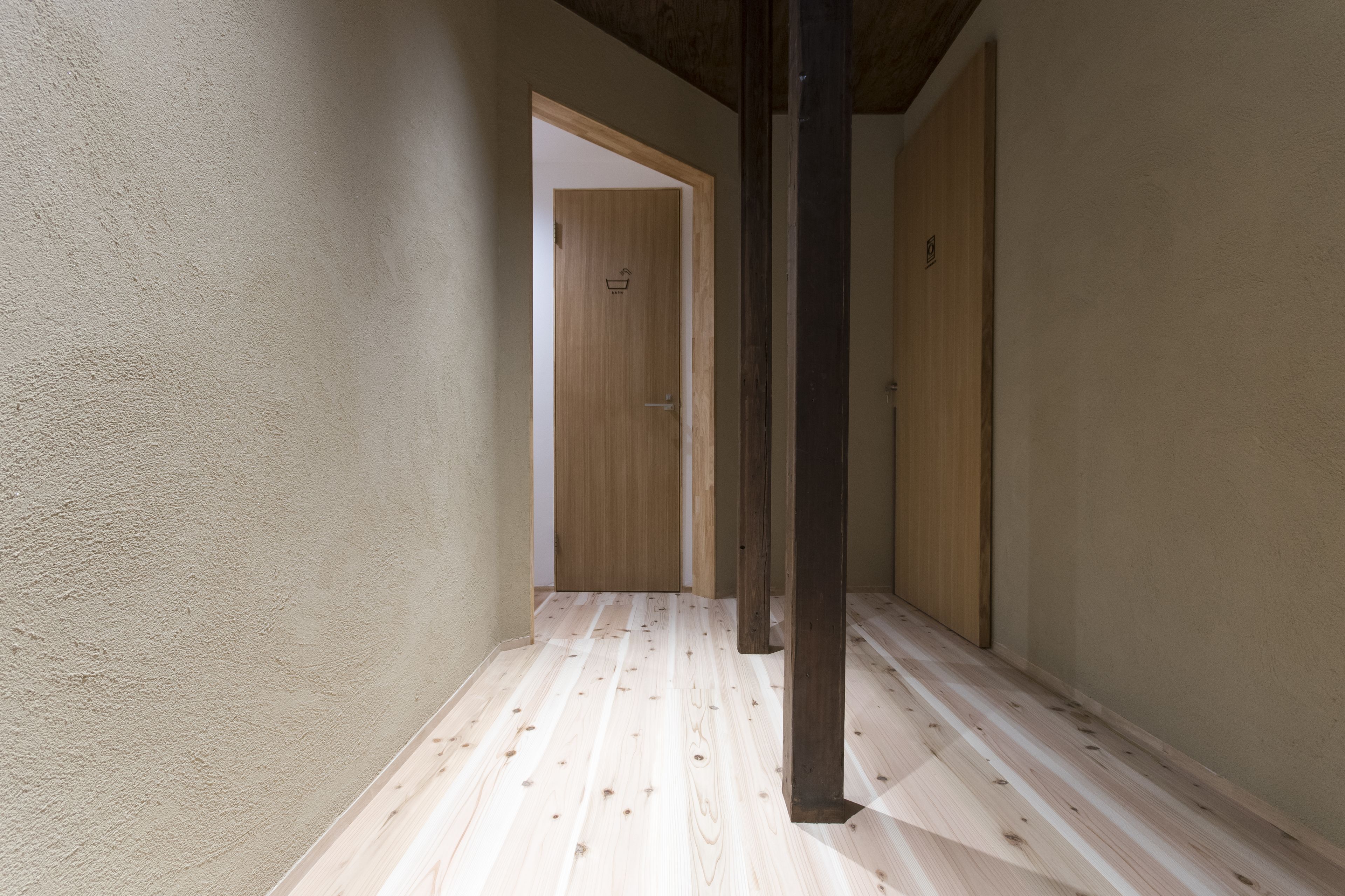 Un pasillo estrecho con suelo de madera y una puerta de madera al final.