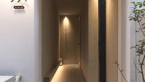 Un couloir avec un luminaire, un panneau indicateur et une plante.