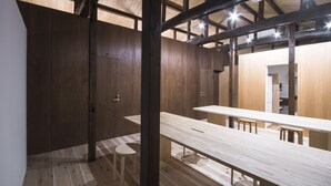 Un intérieur moderne avec des murs et des planchers en bois, une longue table avec des bancs, et une cuisine ouverte.