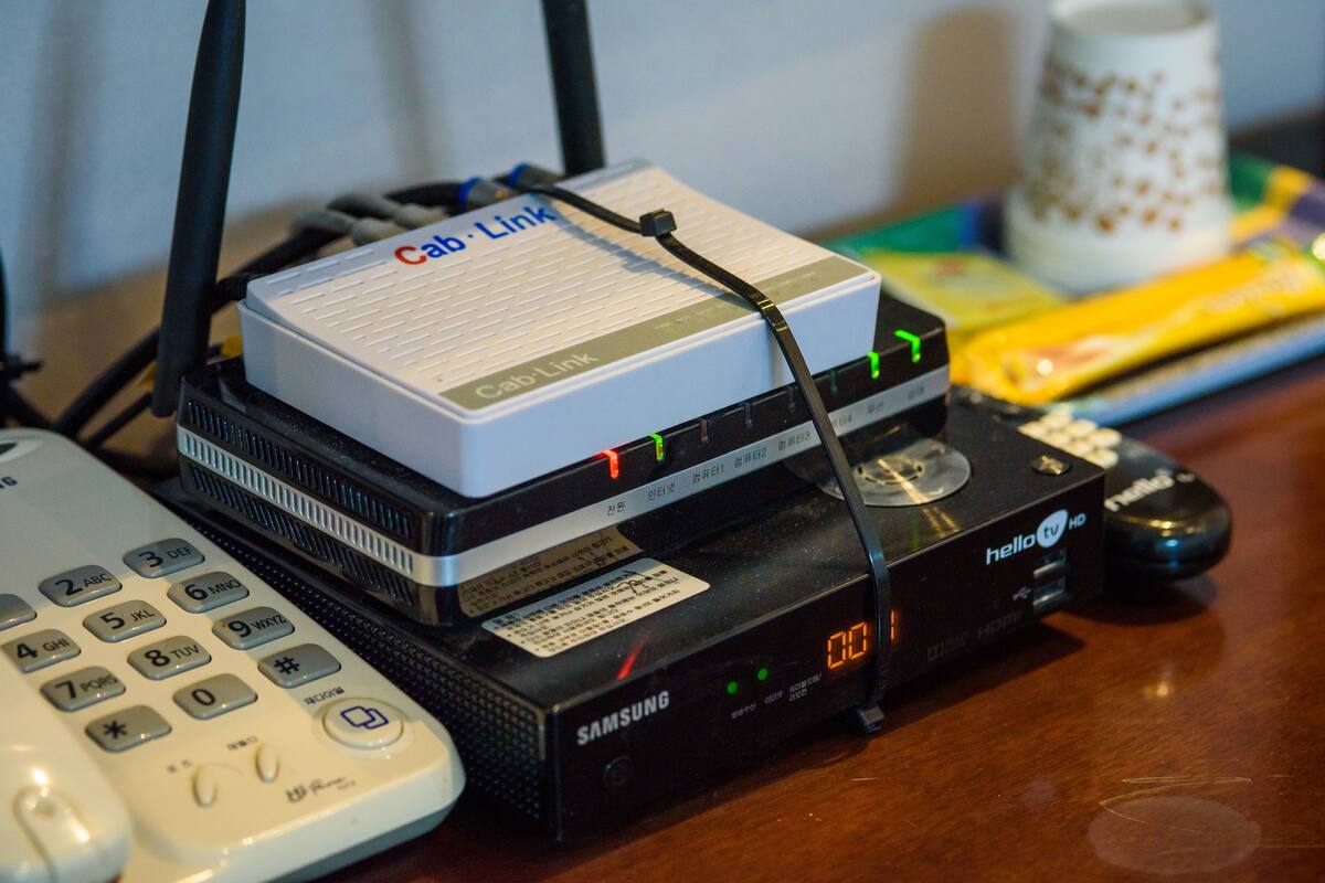 Un dispositivo con la etiqueta 'Cab-Link' y la marca 'Samsung', sobre una superficie de madera junto a un control remoto y un ratón.