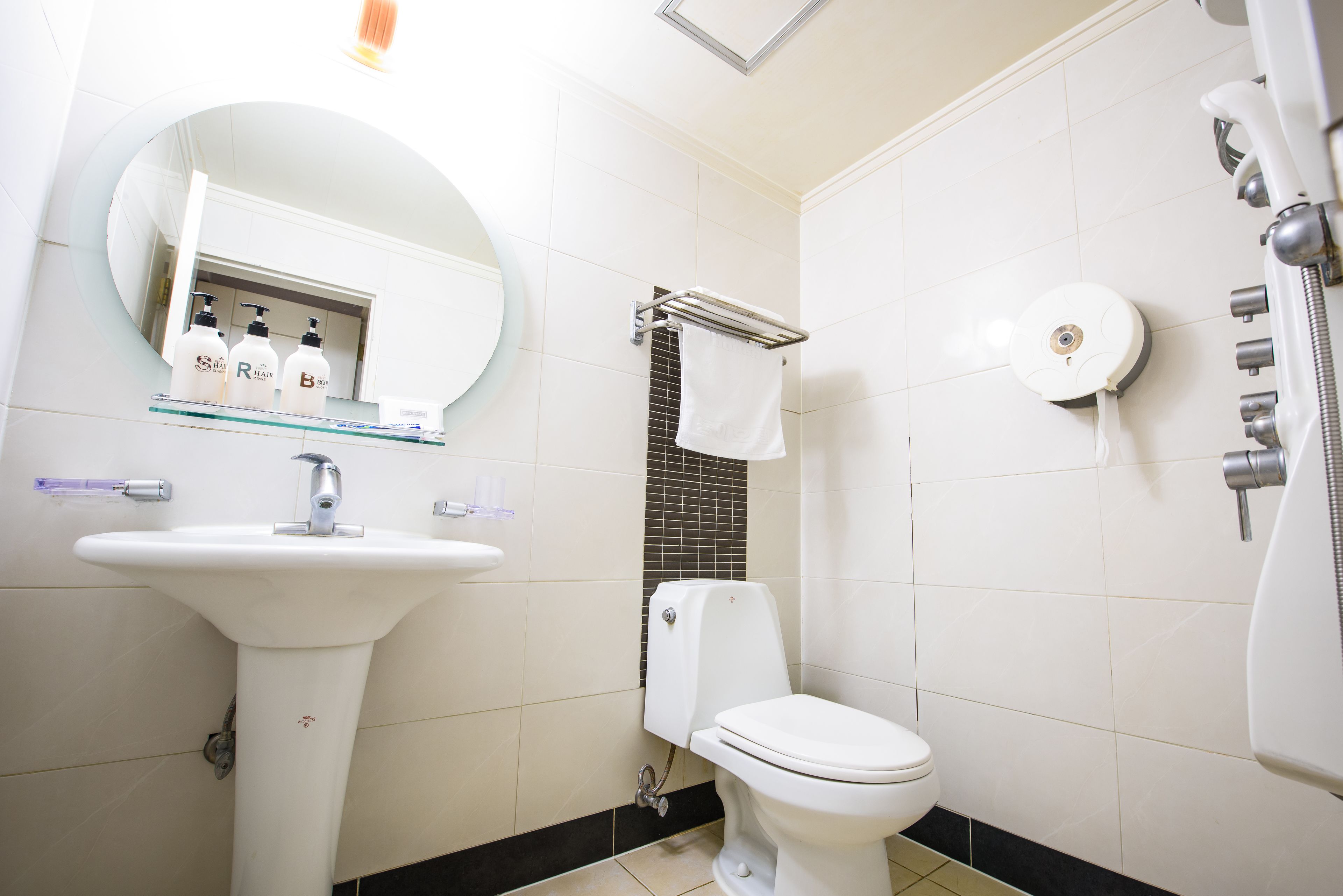 A bathroom with a white sink, a toilet, a mirror, and a towel rack.