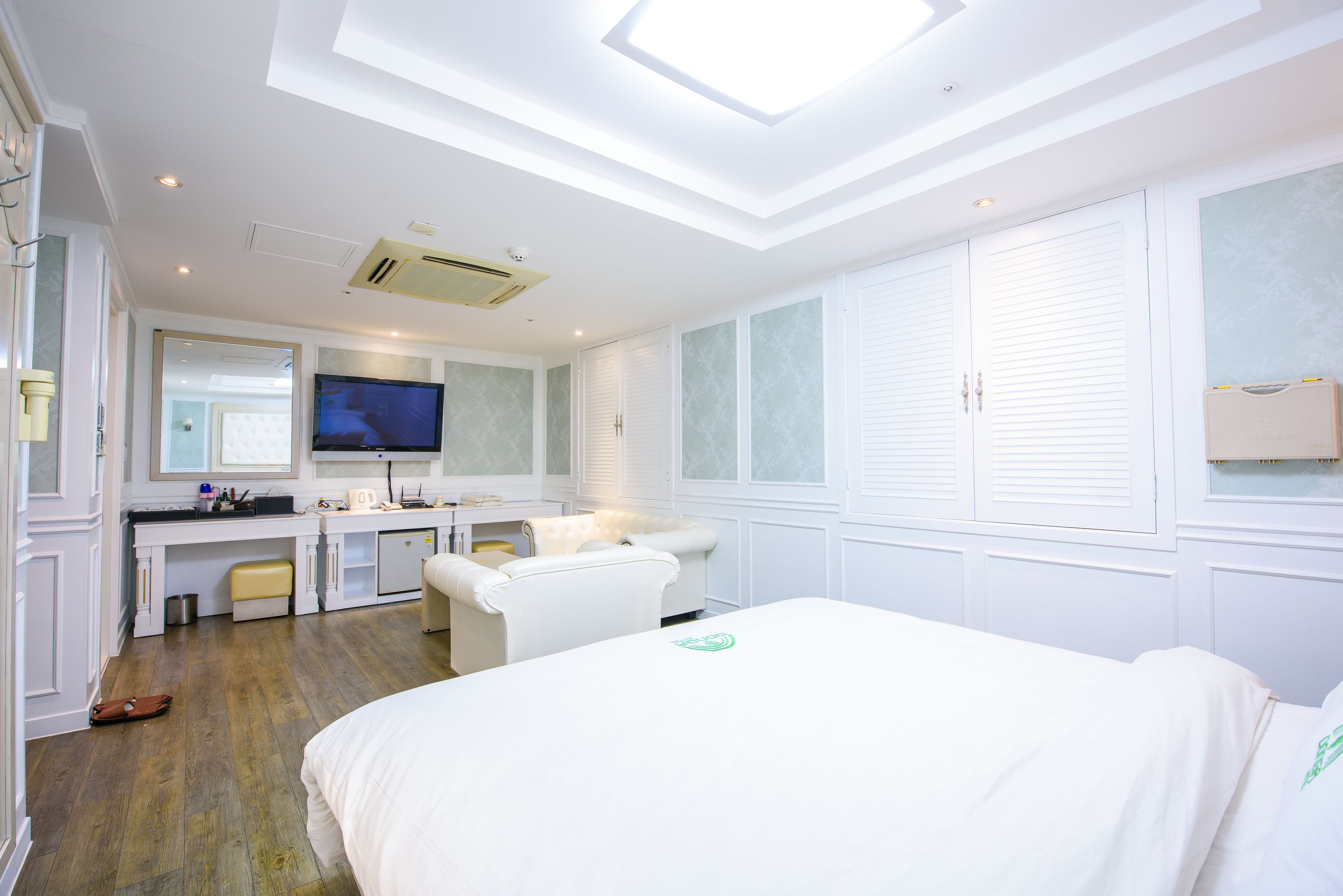 Une chambre d’hôtel moderne dotée d’un grand lit, d’un coin salon, d’une kitchenette et d’une télévision.