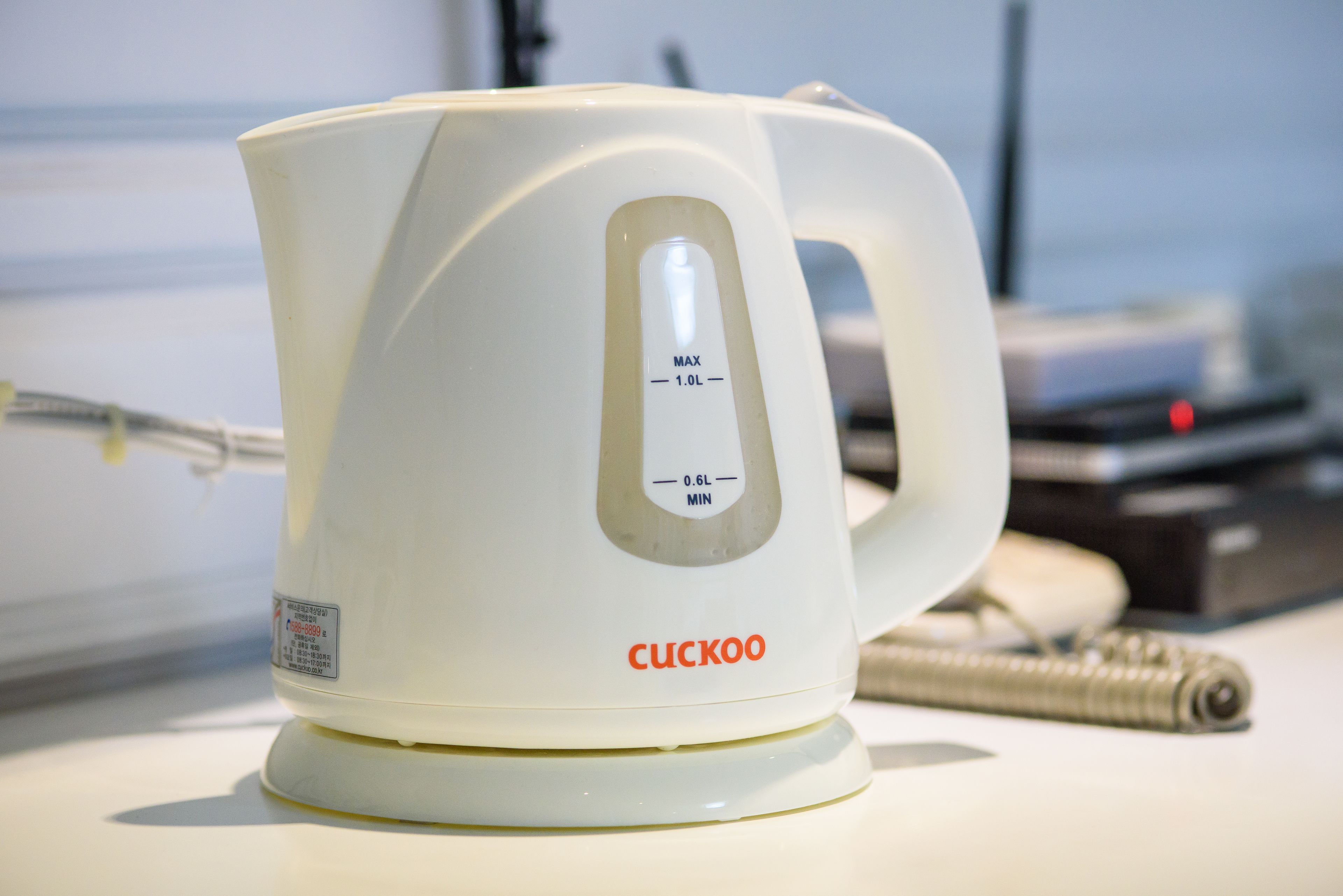 A white electric kettle with measurement markings and the brand name 'CUCKOO' on a table.