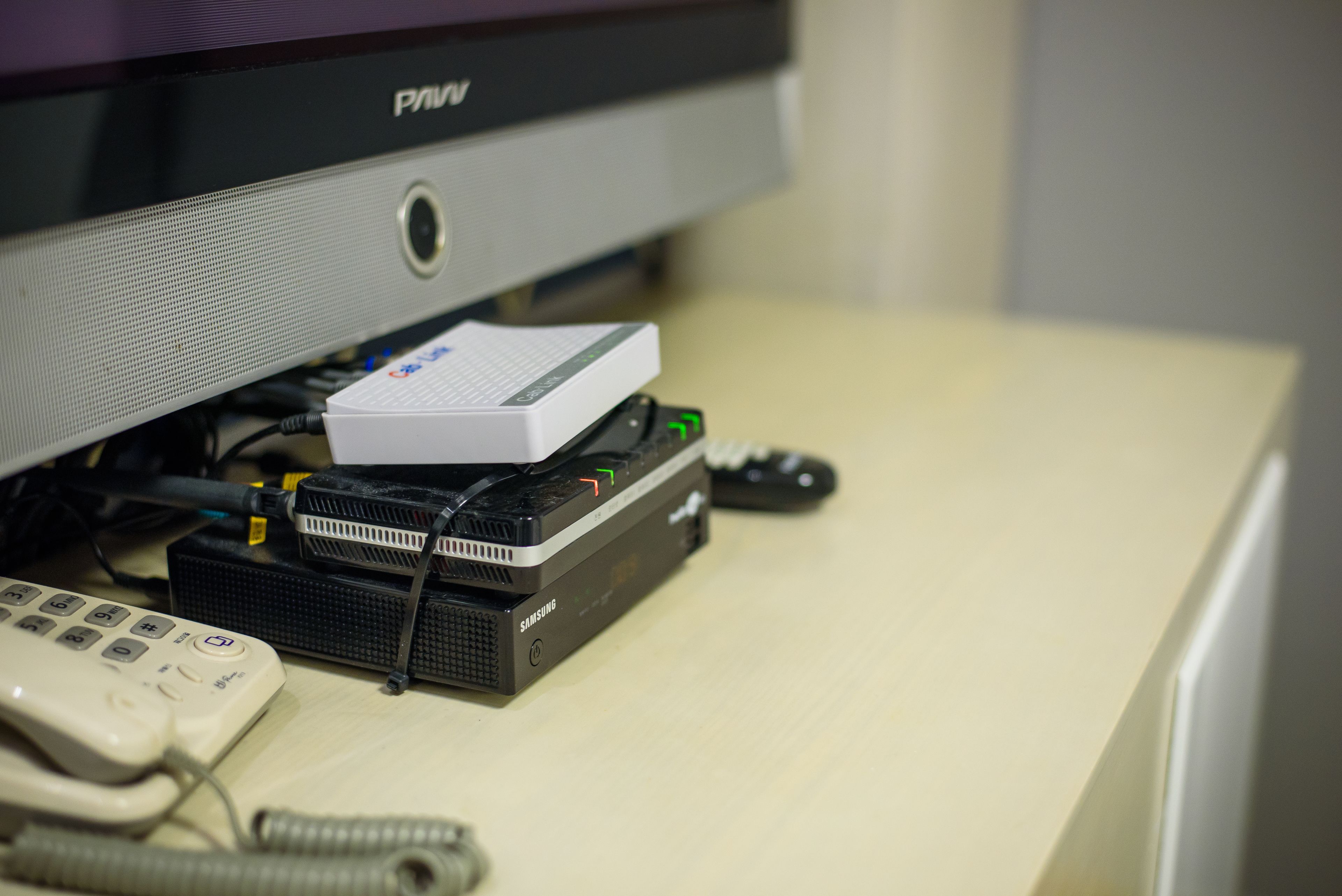A computer monitor, a router, and a telephone on a desk.
