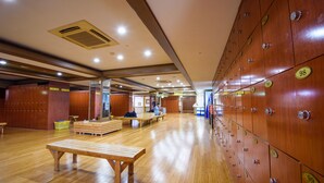 Un vestuario con taquillas de madera, bancos y un banco con un cesto.
