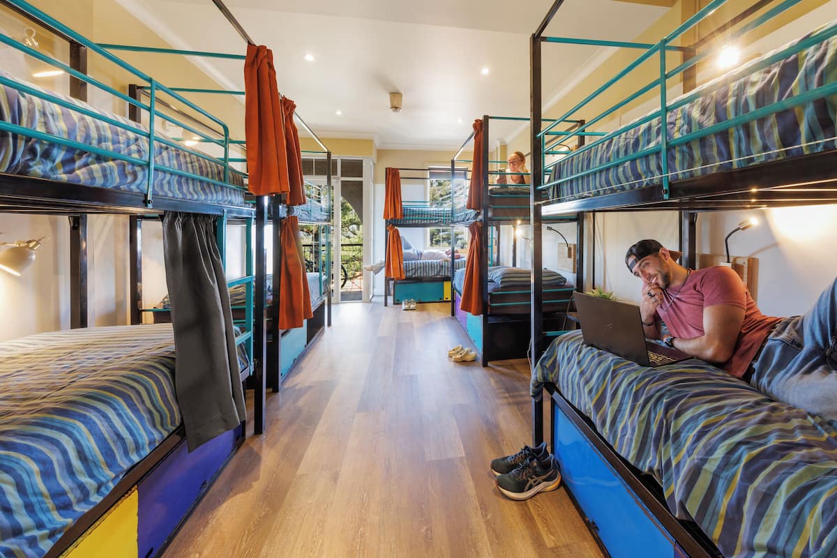 A dormitory room with bunk beds, a laptop on one bed, and a pair of shoes on the floor.