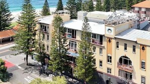 A coastal building with multiple floors, a parking area, and a view of the sea. - Mad Monkey Coogee Beach Hostel (Coogee)