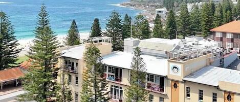 Un edifici a la costa amb diverses plantes, una zona d'aparcament i vistes al mar.