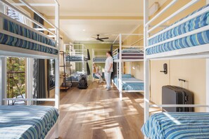 Un dormitorio con literas, un ventilador de techo y una maleta en el suelo.