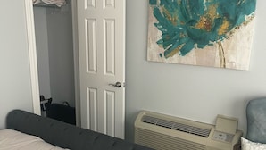 Une chambre à coucher comprenant un lit, une chaise, un radiateur et une porte donnant sur un placard.