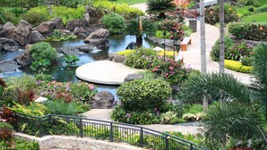 A landscaped garden with a pond, rocks, and various plants. - Discover Ko Olina: Exclusive Deals on Your Dream Vacation in Our 2BR Condo (Kapolei)